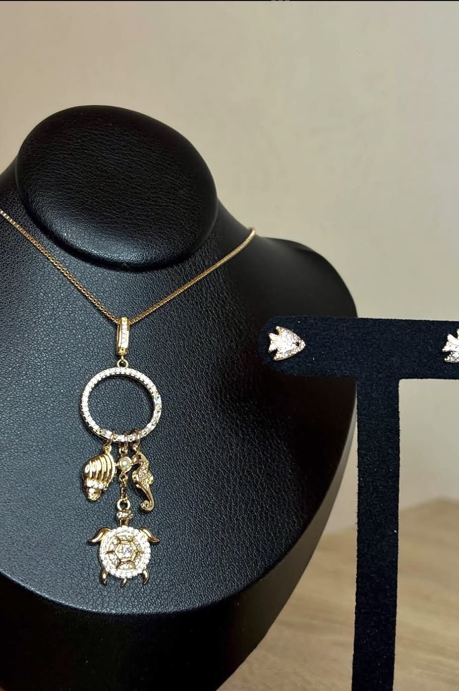 Collana con charms marini e orecchini a forma di pesce su espositori neri