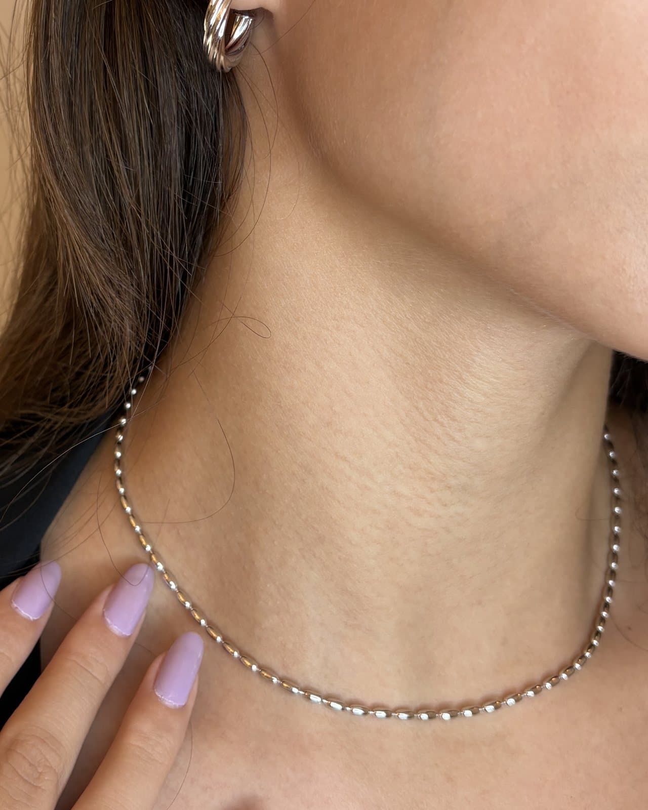 Collana in tono argento a maglia di piccoli grani, indossata