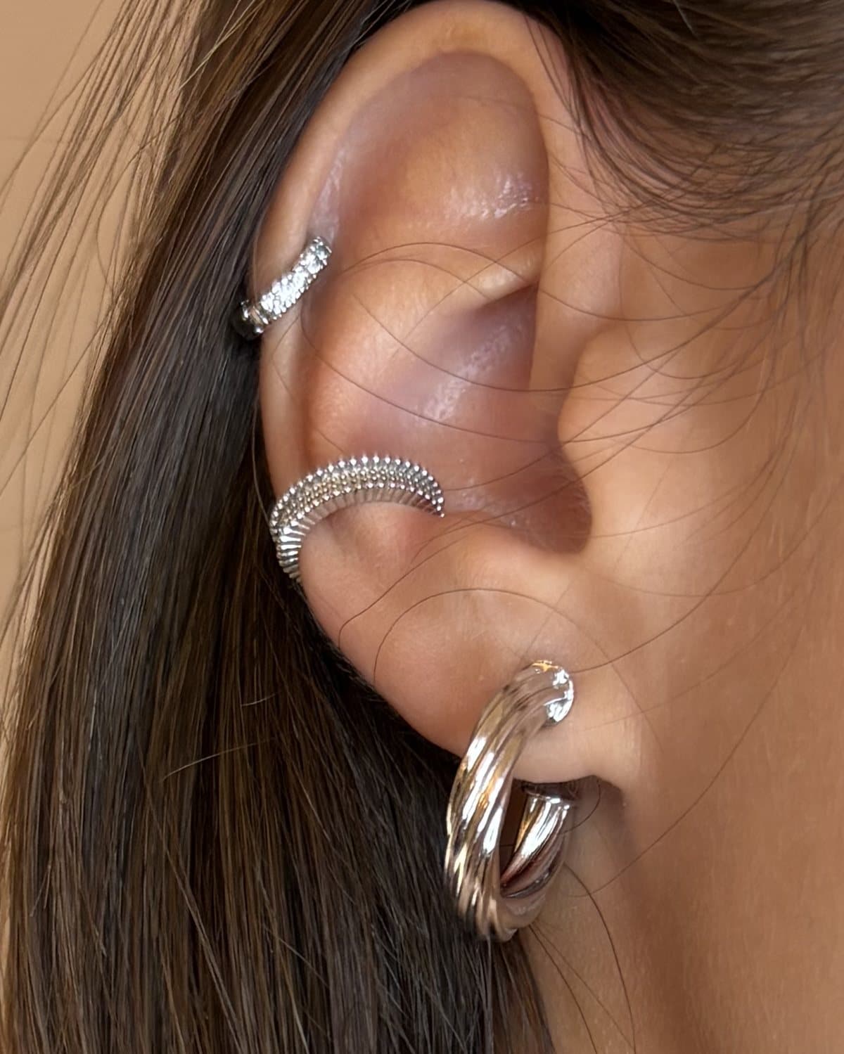 Ear cuff granulato in tono argento al centro dell'orecchio