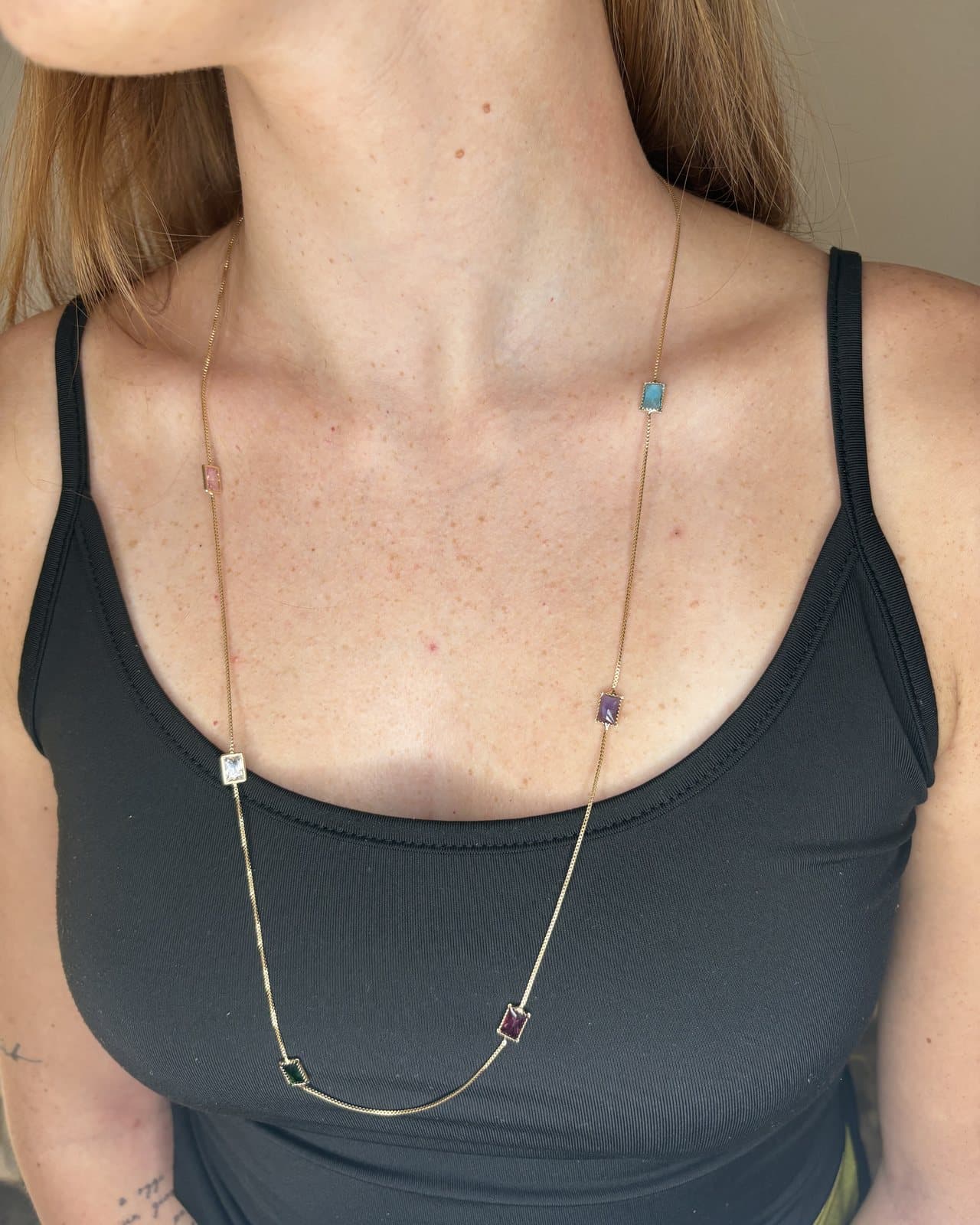 Collana lunga dorata con pietre colorate rettangolari su top nero