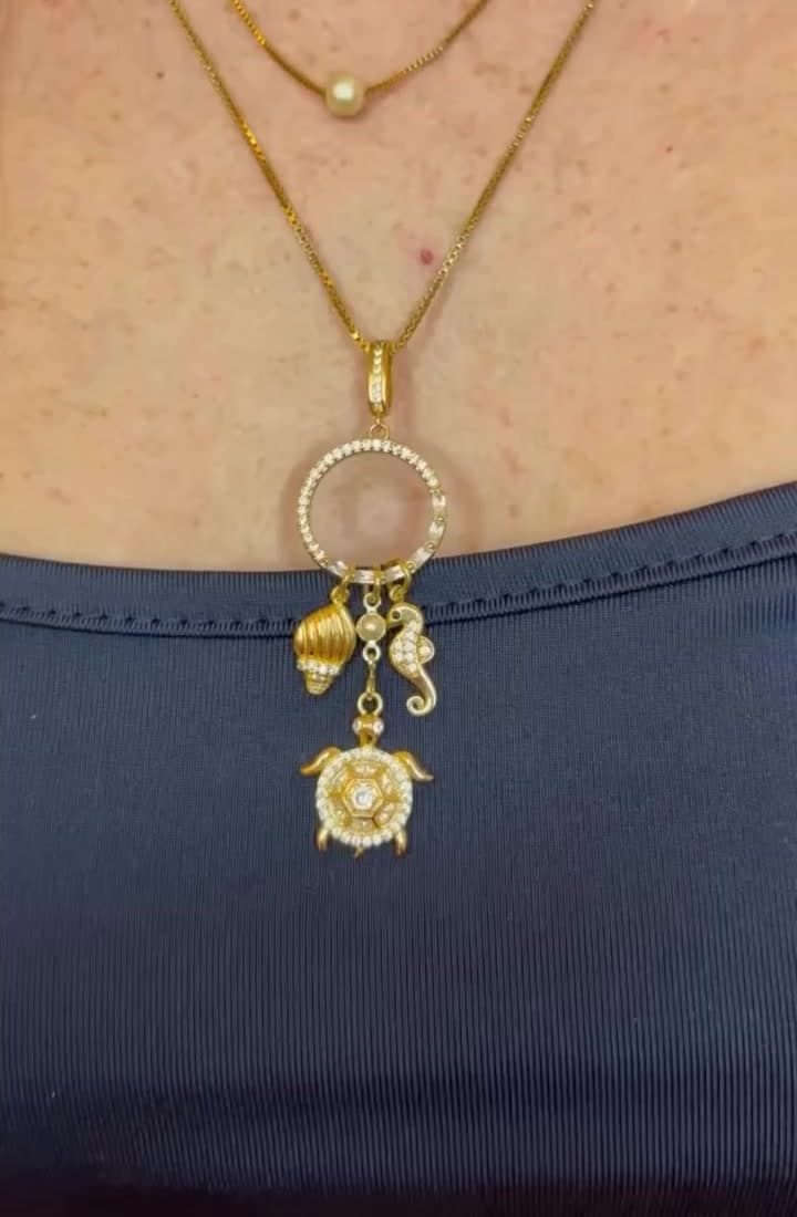Collana dorata con cerchio e charms marini indossata su top blu
