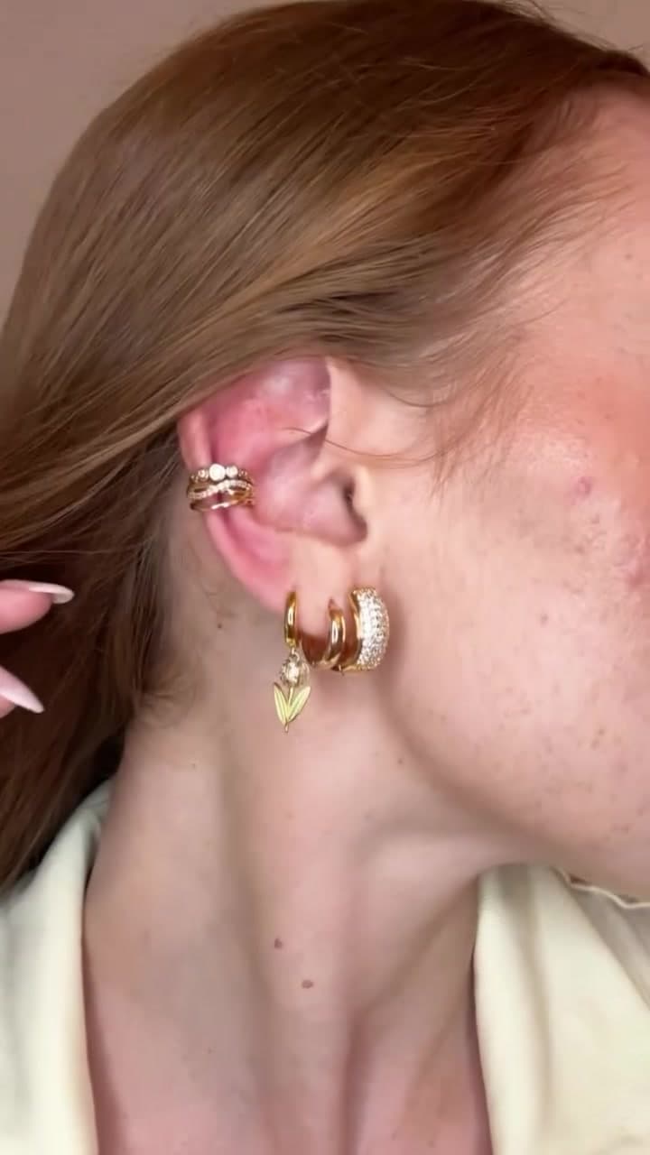 Primo piano dell'orecchio con ear cuff e cerchietti dorati