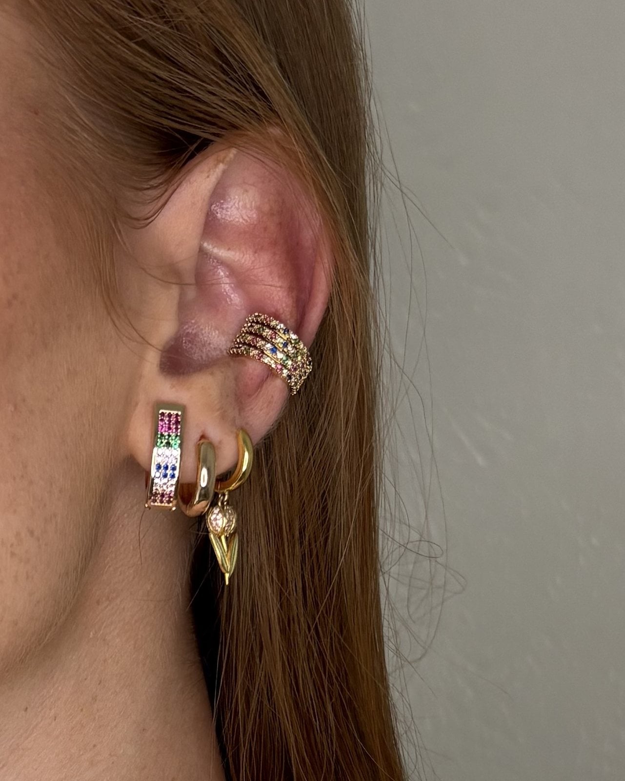 Ear cuff dorato a più fili di zirconi colorati, indossato