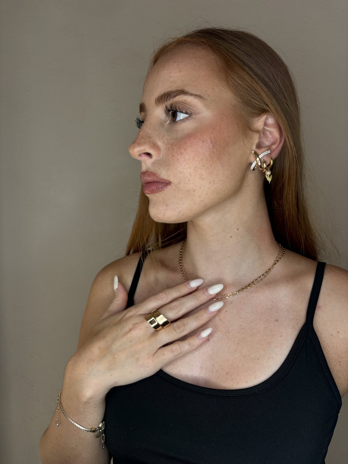 Ritratto con orecchino incrociato bicolore, anello a fascia doppia e collana dorati