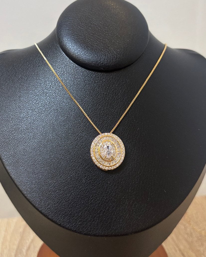 Collana dorata con medaglione di zirconi su busto espositore nero