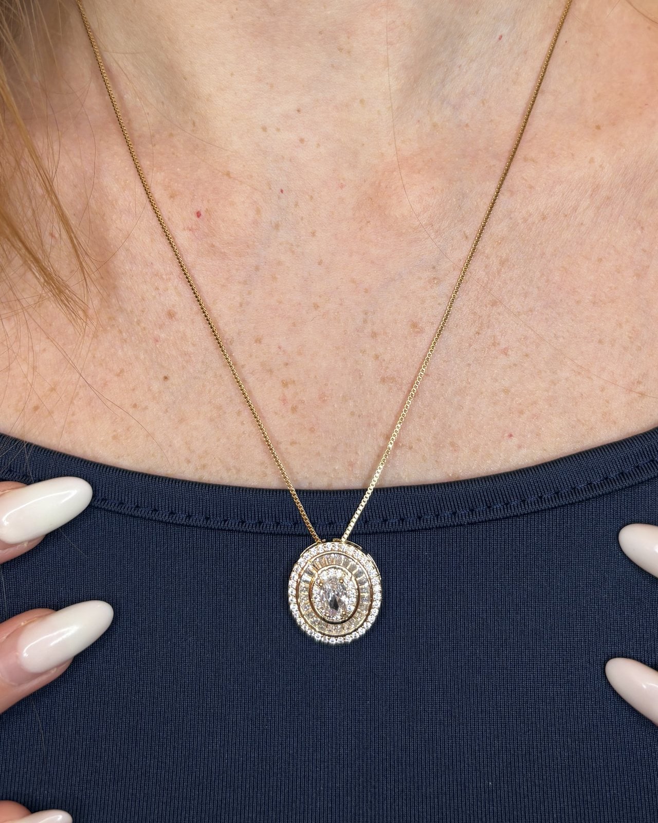 Collana dorata con medaglione di zirconi indossata su top blu