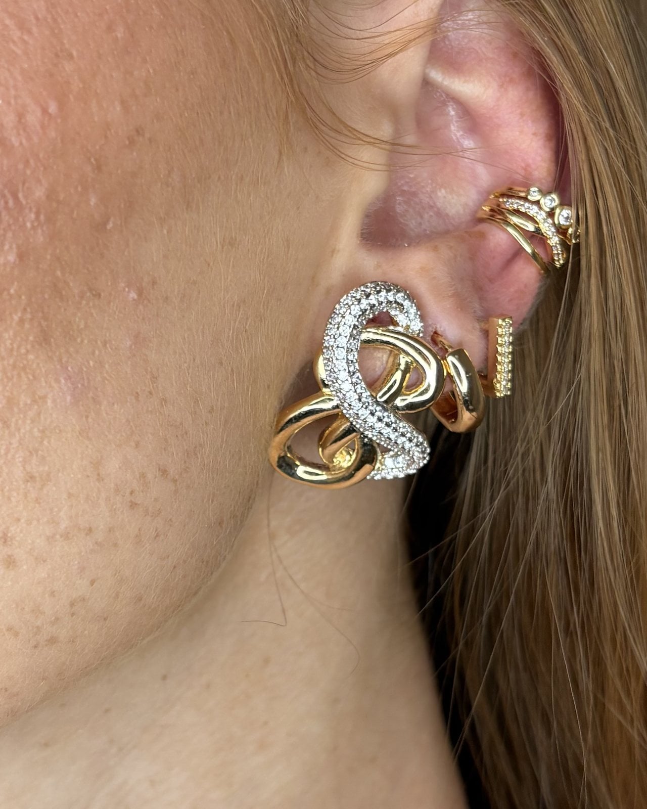 Orecchino a nodo con un anello di zirconi e uno lucido dorato, indossato