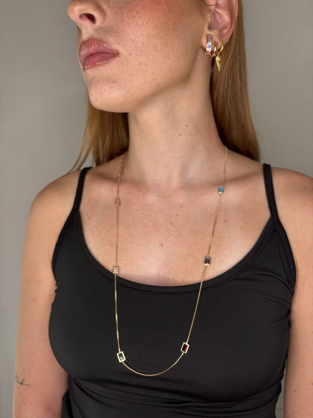 Collana lunga con pietre colorate e orecchini dorati indossati