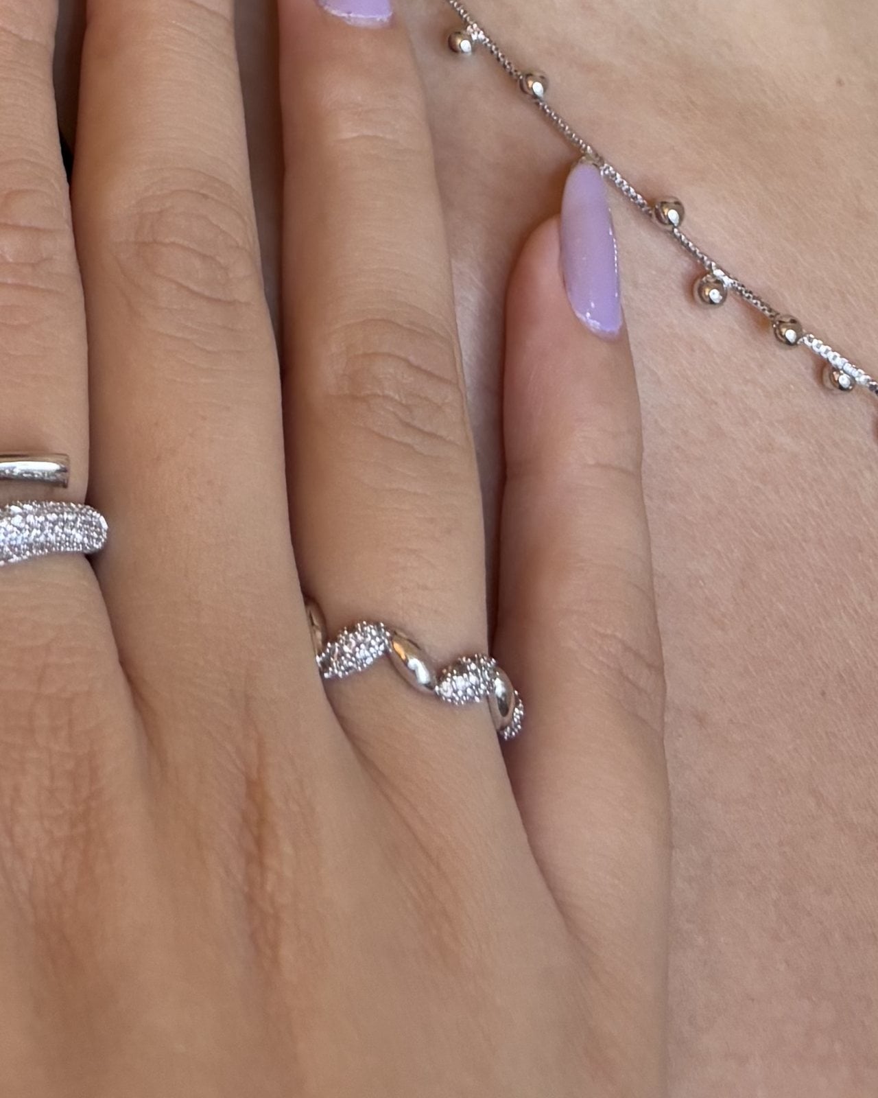 Mano con anello ondulato e fascia con zirconi in tono argento