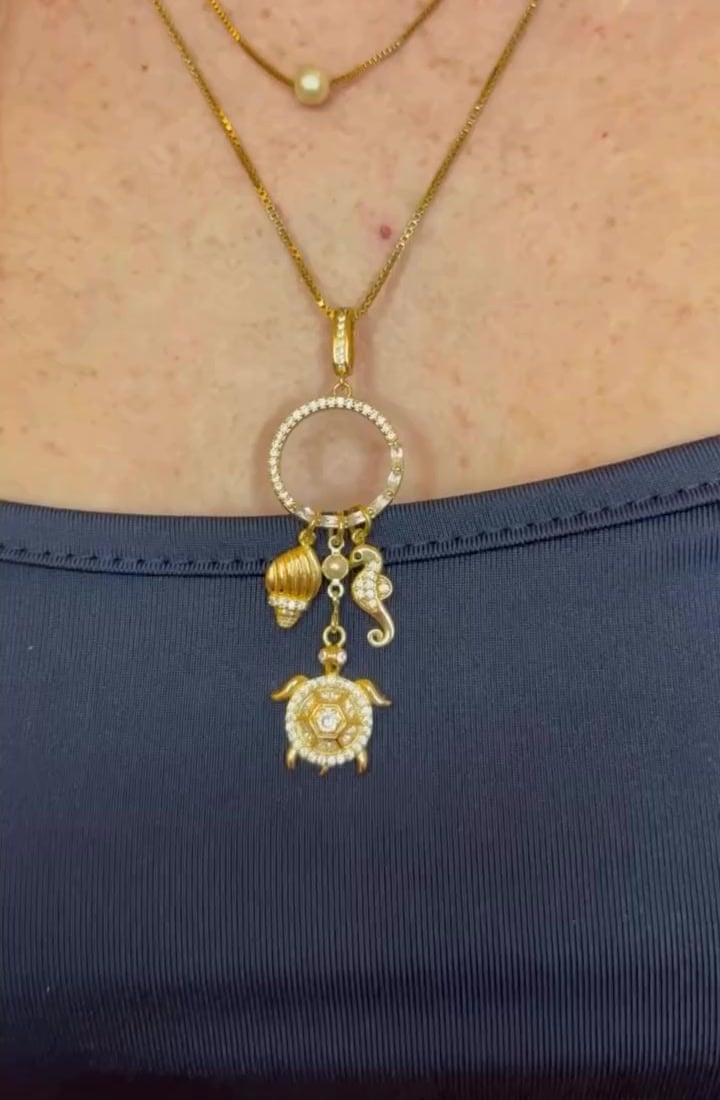 Collana dorata con cerchio e charms marini indossata su top blu